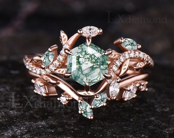 May include: Rose gold ring with a green moss agate gemstone surrounded by smaller clear gemstones and a delicate leafy design.