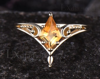 Peut inclure: Une bague en or avec une pierre précieuse orange de forme carrée sertie dans un design délicat et orné.