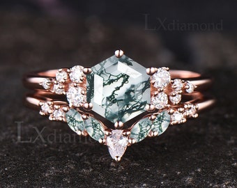 Puede incluir: Un anillo de compromiso de oro rosa con una piedra central hexagonal de ágata verde musgo y un acento de diamante en forma de pera. El anillo está rodeado de diamantes más pequeños.