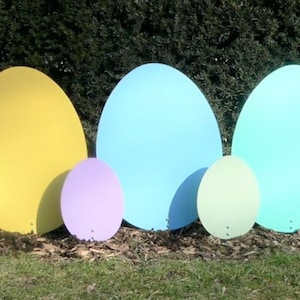 K&ouml;nnte beinhalten: Ein Set aus neun pastellfarbenen Ostereiern aus Pappe in verschiedenen Gr&ouml;&szlig;en. Die Eier sind in einer Reihe auf einer grasbewachsenen Fl&auml;che angeordnet.