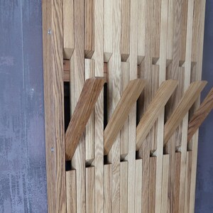May include: A wooden wall-mounted coat rack with multiple hooks. The rack is made of light and dark brown wood slats, creating a unique and modern design.