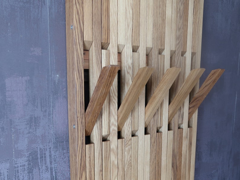 May include: A wooden wall-mounted coat rack with multiple hooks. The rack is made of light and dark brown wood slats, creating a unique and modern design.