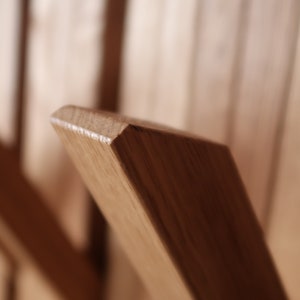 May include: Close-up of a wooden coat rack with multiple hooks. The hooks are made of solid wood and are angled slightly upwards. The wood has a natural, light brown color.