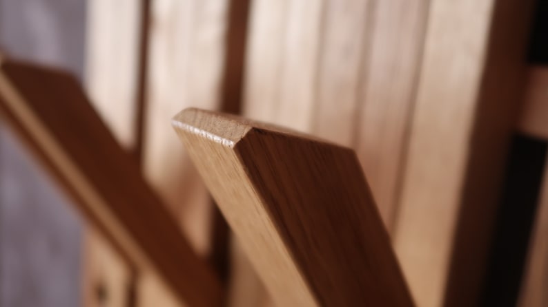 May include: Close-up of a wooden coat rack with multiple hooks. The hooks are made of solid wood and are angled slightly upwards. The wood has a natural, light brown color.