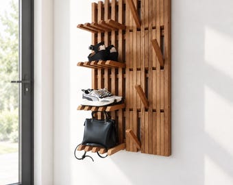 May include: A wall-mounted wooden coat rack and shoe organizer featuring vertical slats, multiple protruding hooks, and two horizontal shelves. The unit holds a pair of black sandals, a pair of white athletic sneakers, and a black handbag.