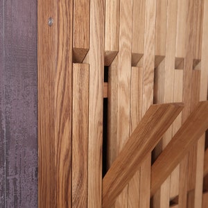 May include: A wooden wall-mounted coat rack with multiple hooks. The rack is made of light brown wood and has a modern design.