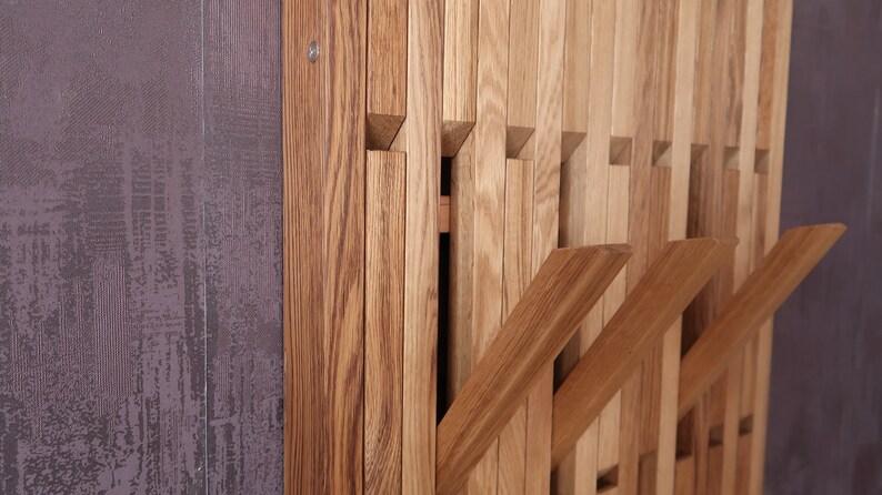 May include: A wooden wall-mounted coat rack with multiple hooks. The rack is made of light brown wood and has a modern design.