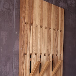 May include: A wooden wall mounted coat rack with multiple horizontal slats. The slats are arranged in a staggered pattern, creating a unique and modern design.