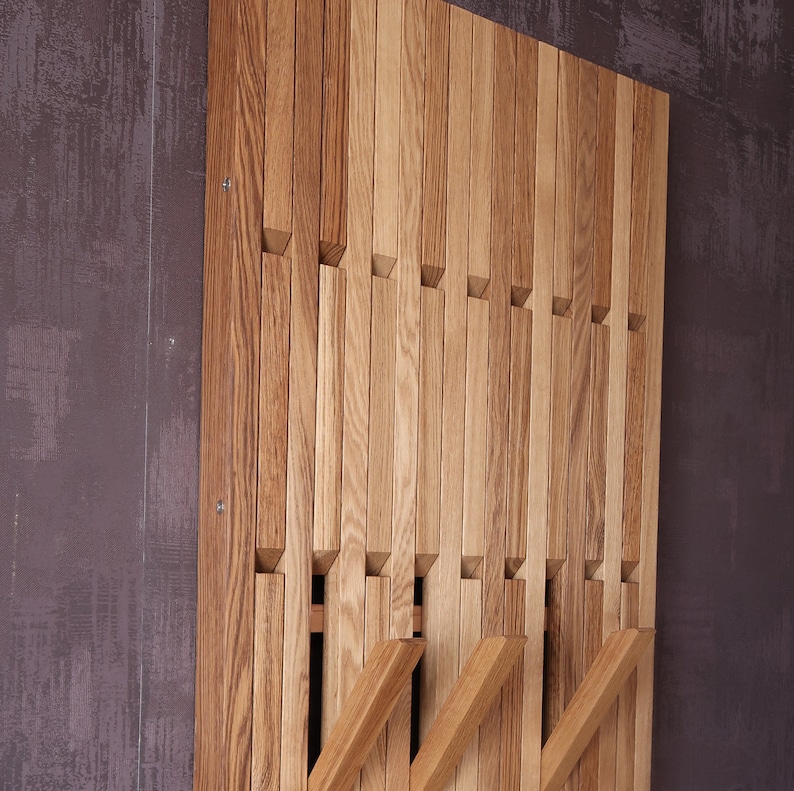 May include: A wooden wall mounted coat rack with multiple horizontal slats. The slats are arranged in a staggered pattern, creating a unique and modern design.