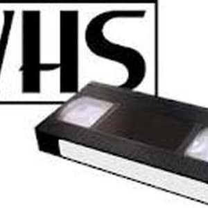 May include: A black VHS video cassette tape with a white label and a white and black "VHS" logo. The rectangular cassette has two white reels visible through the top.