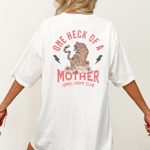 May include: White oversized t-shirt with a red graphic print of a tiger with the text "One Heck of a Mother Feral Moms Club".