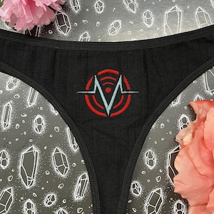 Peut inclure: Sous-vêtements en dentelle noire avec un motif graphique rouge et bleu d'un V stylisé avec un motif d'onde de signal.
