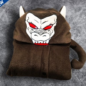 May include: Brown fleece hooded jumpsuit with a monkey face on the hood. The monkey face has red eyes and sharp teeth.