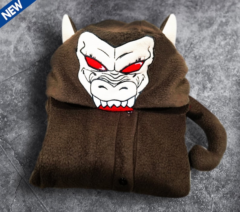 May include: Brown fleece hooded jumpsuit with a monkey face on the hood. The monkey face has red eyes and sharp teeth.