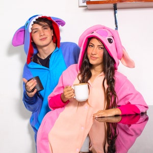 Puede incluir: Dos personas con pijamas de animales azules y rosas est&aacute;n sosteniendo tazas. La persona con el pijama azul est&aacute; sosteniendo una taza negra, y la persona con el pijama rosa est&aacute; sosteniendo una taza blanca.