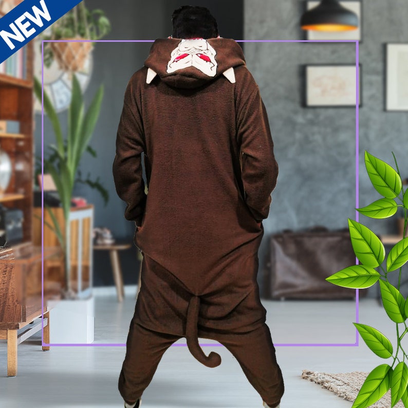 May include: Brown hooded onesie with a monkey face on the hood. The onesie has a tail and is made of soft, plush fabric.