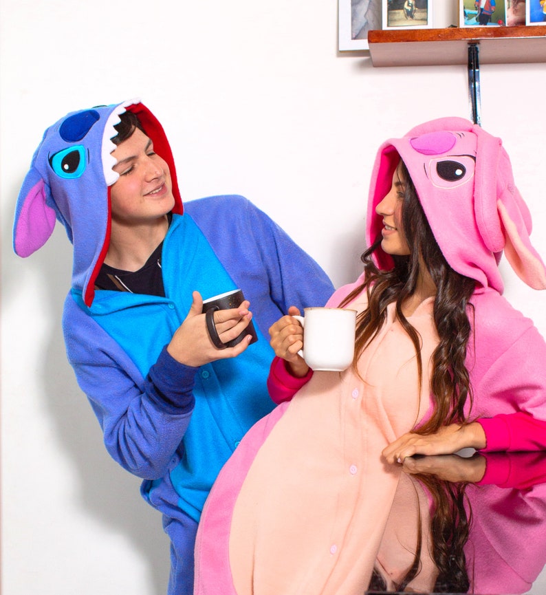 Puede incluir: Dos personas con pijamas de animales con capucha azul y rosa est&aacute;n sosteniendo tazas. La persona con el pijama azul est&aacute; mirando a la persona con el pijama rosa.