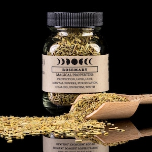 Puede incluir: Un frasco de vidrio lleno de hierbas de romero secas. El frasco tiene una tapa negra y una etiqueta marrón con el texto "ROSEMARY" y "MAGICAL PROPERTIES: PROTECTION, LOVE, LUST, MENTAL POWERS, PURIFICATION, HEALING, EXORCISM, YOUTH".