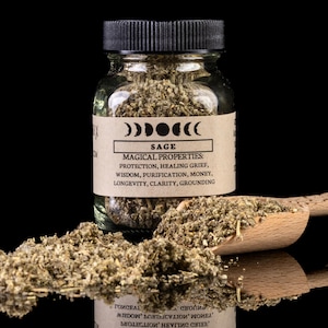 Puede incluir: Un frasco de vidrio lleno de hojas de salvia secas. El frasco tiene una tapa negra y una etiqueta marrón con las palabras "Salvia" y "Propiedades mágicas" impresas en ella. La etiqueta también enumera las propiedades mágicas de la salvia, que incluyen protección, sanar el dolor, sabiduría, purificación, dinero, longevidad, claridad y conexión a tierra.