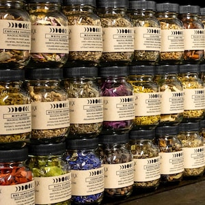 May include: A collection of small glass jars filled with dried herbs and flowers. Each jar has a label with the name of the herb or flower and its magical properties. The jars are arranged in rows on a wooden shelf.
