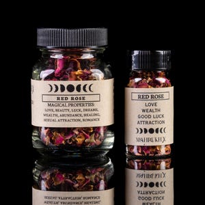 May include: Two glass jars filled with dried red rose petals. The jars have black lids and labels with the words "Red Rose" and "Magical Properties". The labels list properties such as love, beauty, and wealth.