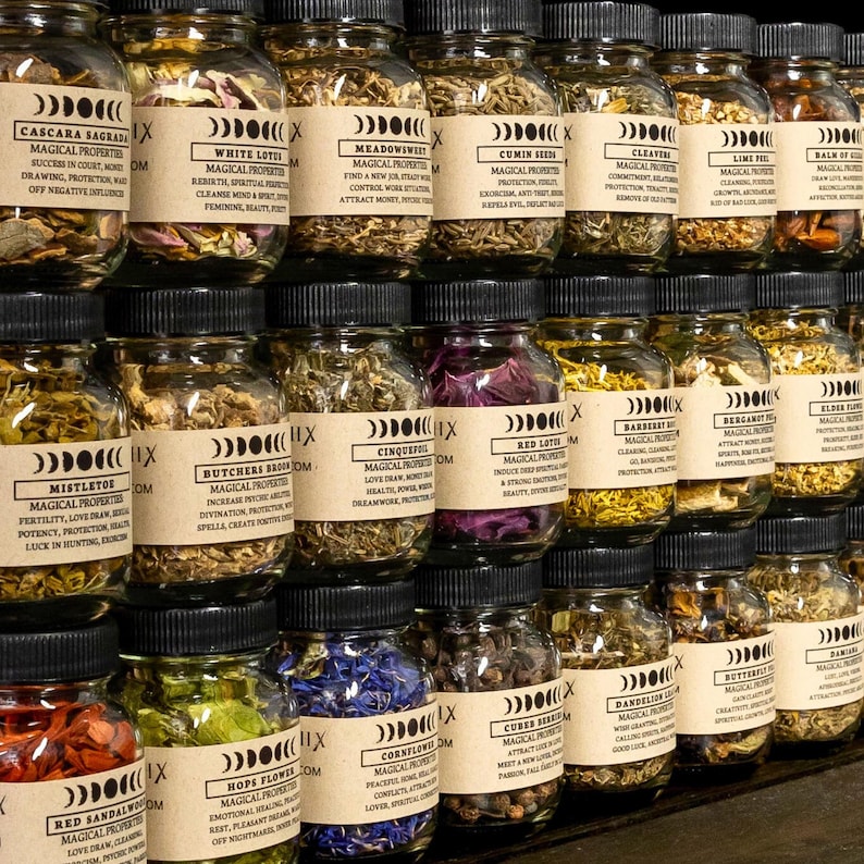 May include: A collection of glass jars filled with dried herbs and botanicals. Each jar has a black lid and a label with text describing the contents and their magical properties. The jars are arranged in neat rows, creating a visually appealing display.
