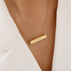 Peut inclure: Un collier avec une barre en or gravée du nom "LAURA".
