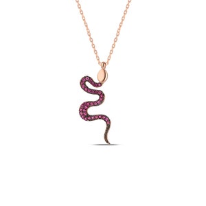 May include: A rose gold necklace featuring a pink snake pendant. The snake is adorned with small pink stones.