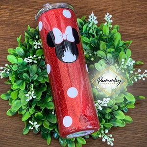 May include: Red glitter tumbler with white polka dots and a black and white Minnie Mouse design. The tumbler has a black lid and a silver straw.