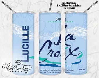 May include: A light blue 20 oz tumbler with a straw, featuring the name "LUCILLE" in teal and a "Pao Monkey Creations" logo. The design includes "La Croix" branding and text indicating it's sparkling water, with no calories or artificial sweeteners.