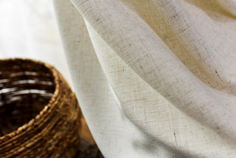 May include: Close-up of a white linen curtain with a textured weave. The curtain is draped and folded, creating soft folds and shadows.
