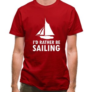 Peut inclure: T-shirt rouge avec un graphique de voilier blanc et le texte "I'd rather be sailing".