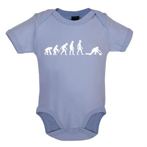 Könnte beinhalten: Hellblaues Baby-Body mit weißer Grafik, die die menschliche Evolution zum Curling zeigt. Der kurzärmelige Body hat einen Druckknopfverschluss. Die Grafik zeigt die Entwicklung von affenähnlicher zu menschlicher Form.