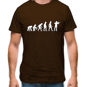 Puede incluir: Una camiseta marrón con un gráfico blanco de la evolución del hombre, que termina con un hombre tocando el violín.