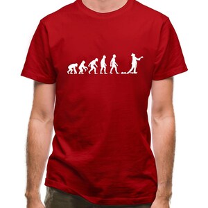 May include: A red t-shirt with a white graphic of the evolution of man, ending with a man holding a metal detector.