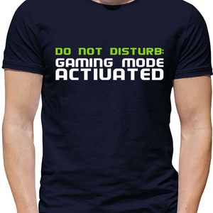 May include: A navy blue t-shirt with white text that reads "DO NOT DISTURB: GAMING MODE ACTIVATED" in a green box.