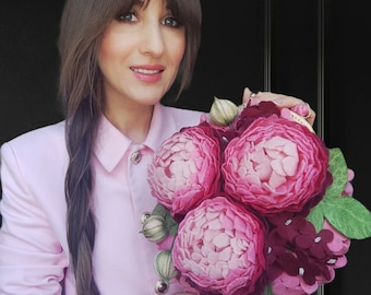 May include: A pink felt flower clutch bag with three large pink peonies and smaller pink and burgundy flowers. The bag has a pink cord handle.