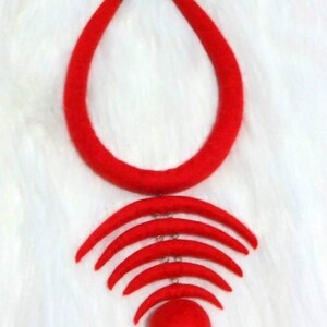 May include: A red felt necklace with a large circle pendant and a series of smaller crescent moon shapes hanging from it.