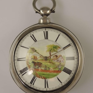 Può includere: Orologio da tasca in argento con una scena dipinta di un aratro trainato da cavalli in un campo. Il quadrante dell'orologio ha indici orari con numeri romani.