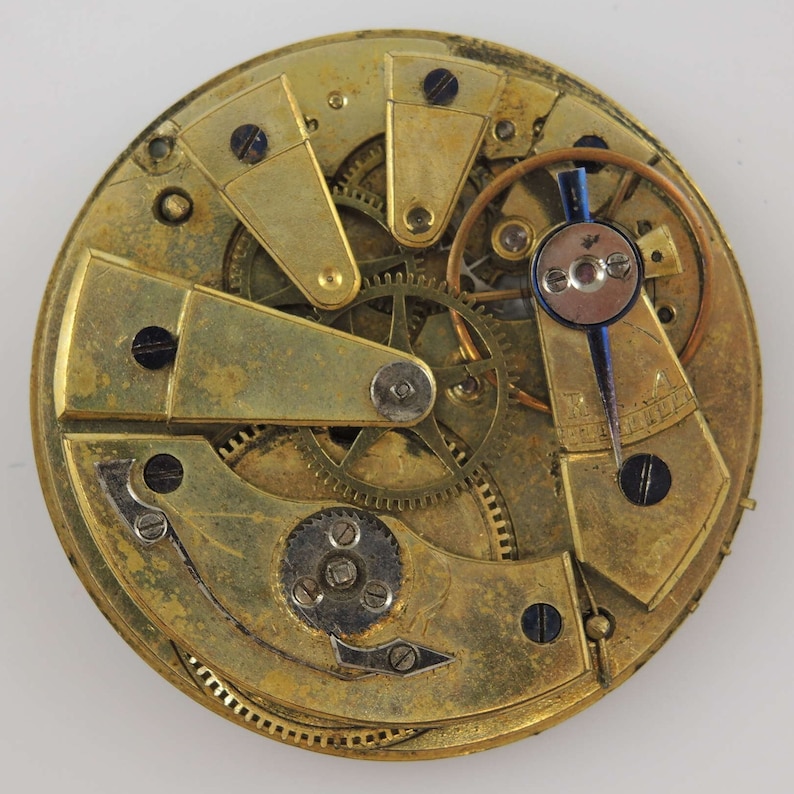May include: Close-up of a gold-toned pocket watch movement with intricate gears and levers. The watch face is visible in the background.