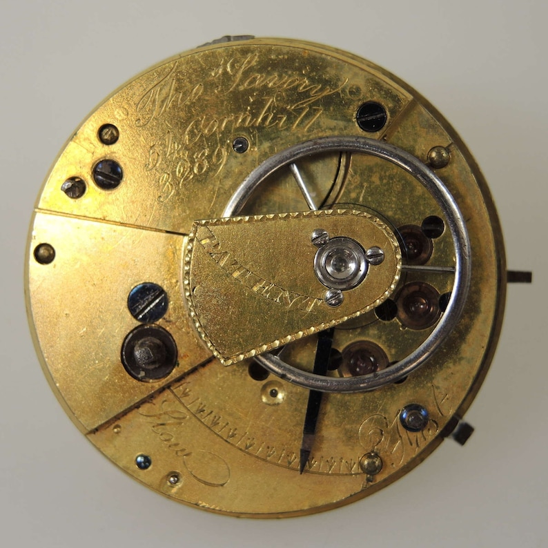 Puede incluir: Primer plano del mecanismo interno de un reloj de bolsillo de oro. La esfera del reloj est&aacute; inscrita con "Mr. Lowry & Son, Cornhill, London, 1889".