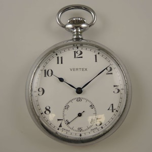 May include: A silver pocket watch with a white face and black hands. The watch has a black second hand and a small subdial for seconds. The watch face says "VERTEX" and "SWISS MADE".