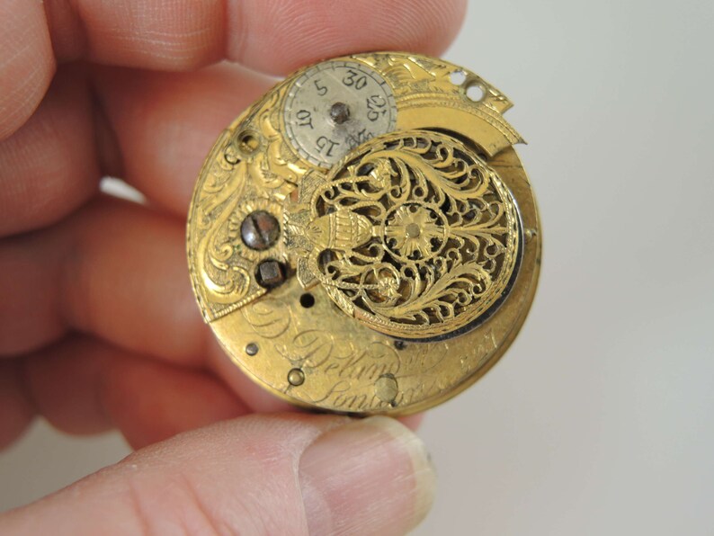 K&ouml;nnte beinhalten: Eine goldene Taschenuhr mit aufwendigen floralen Gravuren auf der R&uuml;ckseite. Das Zifferblatt der Uhr ist sichtbar und hat r&ouml;mische Ziffern f&uuml;r die Stunden.