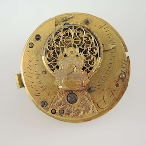 K&ouml;nnte beinhalten: Nahaufnahme eines antiken Uhrwerks aus Gold mit aufwendigen Filigran- und Gravurdetails. Der Uhrenmechanismus zeigt ein dekoratives Schwanen-Emblem und die Inschrift "H-A Hampton". Das Zifferblatt hat ein kreisf&ouml;rmiges Design mit sichtbaren Zahnr&auml;dern und Schrauben.