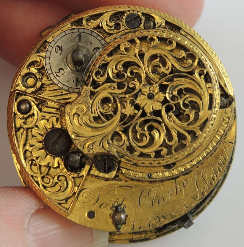 May include: A gold pocket watch with intricate floral engravings and the inscription "Nath. Clarke London 11498".