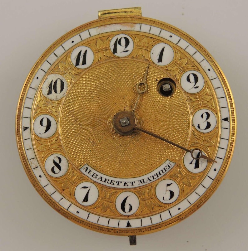 Puede incluir: Una esfera de reloj de bolsillo de oro con marcadores de hora en n&uacute;meros romanos y una esfera de esmalte blanco. La esfera del reloj est&aacute; grabada con un dise&ntilde;o floral y el texto "ALBARET ET MATHIEU".