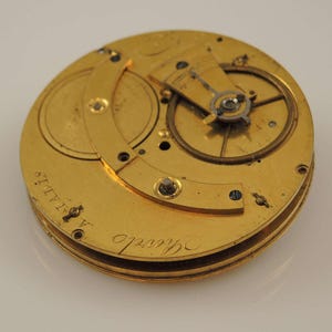 May include: A gold pocket watch movement with intricate gears and a circular plate with the inscription "Saville" and "A. HALLS."
