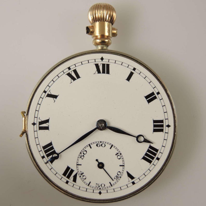 Puede incluir: Un reloj de bolsillo vintage con esfera blanca, n&uacute;meros romanos negros y manecillas negras. El reloj tiene un peque&ntilde;o dial de segundos y una corona y detalles dorados. La caja del reloj es de color plateado.