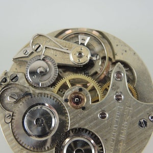 May include: Close-up view of the inner workings of a silver pocket watch. The watch face is visible with the text "G.S. SMITH PHILADELPHIA" printed on it.