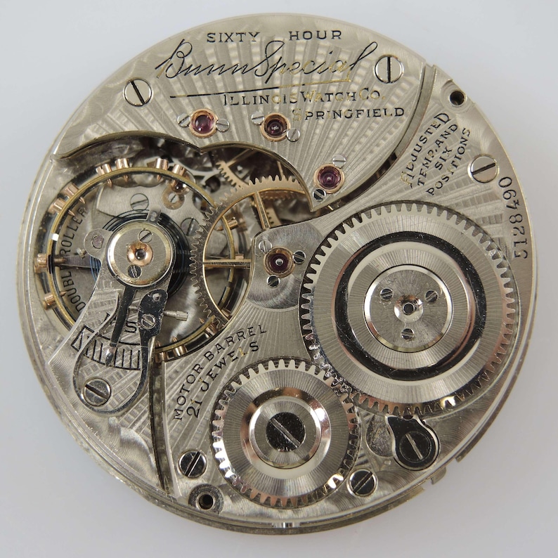 May include: Detailed view of a vintage watch mechanism, showcasing numerous gears and intricate components. The watch movement is marked with "Bunn Special" and "Illinois Watch Co. Springfield". It also features "Double Roller" and "Motor Barrel 21 Jewels" inscriptions.